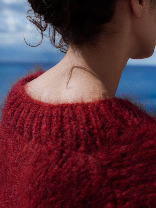 Person wearing a red knitted sweater with a blurred background